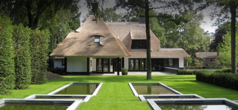 Vrijstaande villa met rieten kap, glazen pui en een strakke tuin met waterpartijen