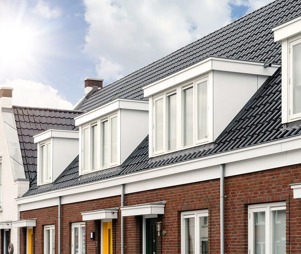 Rij woningen met witte dakkapellen onder een zwart pannendak