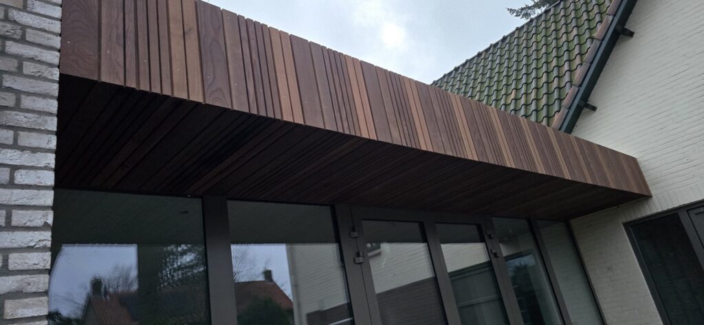 Overkapping met houten gevelbekleding boven een glazen pui